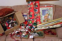 Photo showing multiple gift ribbons, bows, and several rolls of holiday-themed wrapping paper along with gift bags and holiday gift tags.
