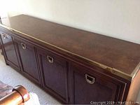 Full side view of the cherry wood buffet with brass trim, showing cabinet doors and brass handles.