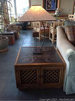 End table with walnut finish, black engraved patterned top, and braided cabinet doors