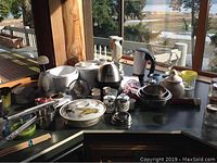 Wide view of kitchen accessories showing various items including mixers, salad spinner, bowls, jars, and utensils arranged on counter.