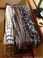 Six scarves laid side by side showing neutral stripes, solid tones and abstract black-and-white pattern.