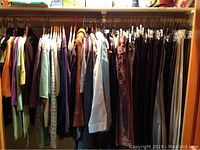 Full closet rack showing assorted garments on wooden and clear hangers