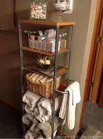 Tall shelving rack with towels folded and stacked on shelves and hanging from side towel bars.