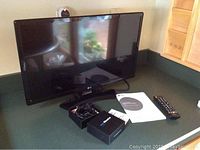 LG 21 inch flatscreen TV on counter with remote, innoTronics Wireless Adapter Kit in box with cables, and user manuals visible