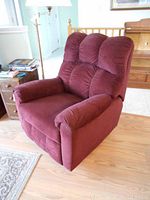 Side angle view of the burgundy rocker recliner showing padded armrest and plush fabric upholstery.
