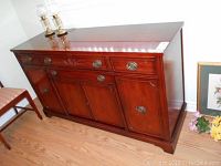 Full front view showing the sideboard's drawers and cupboards with brass hardware and carved detailing on the middle top drawer