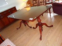 Mahogany dining table from an angled view showing pedestal legs and claw feet.