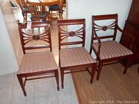 Set of three wooden dining chairs and one armchair showing carved medallion backrests and upholstered seats.