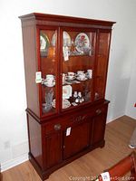 Full view of mahogany china cabinet with glass paneled upper hutch and closed base section showing drawer and cupboard door