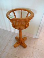 Front view of wooden plant stand showing circular top and three-legged base