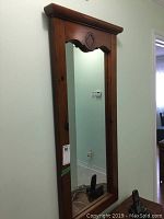 Full view of rectangular wood framed mirror standing on floor against wall