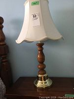 Full view of one lamp showing turned wood and brass base with white cloth shade