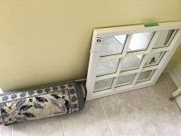 Two small rolled floor mats with blue and gray floral pattern leaning against the wall next to the mirror.