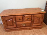 Front view showing two side compartments with paneled doors, two small central drawers, one larger bottom drawer, brass handles