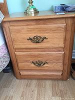 Front view of Shermag solid oak night table showing two drawers with decorative metal hardware and oak grain finish