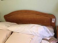Photo of the oak headboard attached to the bed frame, showing wood grain and curved design.