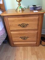 Front view of Shermag solid oak night table with two drawers and brass handles.