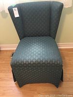 Front view of green fabric slipper chair showing wingback and fabric pattern.