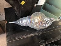 Iridescent hanging glass shell decoration with swirl pattern reflecting light