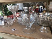 Wide view of all six crystal serving pieces on a countertop showing cake dish, trifle dish, bowls with cut designs.