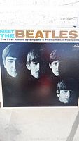 Front cover of 'Meet The Beatles' album showing band members' faces and title text