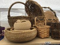 Photo showing various baskets on table including large handled baskets and small rectangular handled basket.