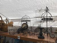 Photo showing various metal decorative items on a table including basket styles, metal racks, and candle holders under a tent.