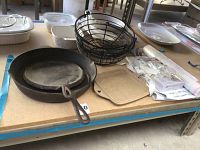 Cast iron skillet and griddle on corner of table with metal baskets, a stack of piping paper and tips, and square ceramic dish all displayed.