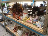Shelf with assorted holiday decorations in ceramic, glass, and fabric, including ghost cookie jar, chick, bunny figurines, and small bowls.