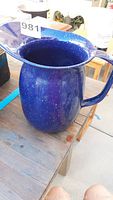 Blue speckled enamel pitcher shown from top angle highlighting wide spout and handle