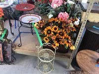 View of the ceramic birdbath or feeder on metal stand, tin container with faux flowers in the background