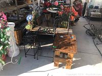 Overview of the five pieces including metal plant stands, wooden bench, wooden table, and plant rack in an outdoor setting with floral surroundings.