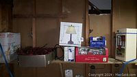 Photo showing wreath and some boxed lighting and decor items on a shelf