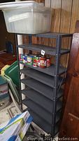 Full view of black metal shelving unit with plastic storage bins and cans visible on third shelf, food not included.