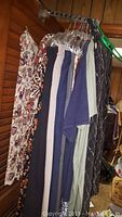 Photo showing multiple women's plus size clothing items hanging on a rack, including floral dresses or skirts, and solid color pieces in navy and blue.