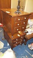 Photo of stacked wood side tables showing six drawers each with round white ceramic pulls, wood grain visible, with some scuffs and scratches.