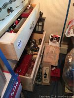 Open drawers showing silver plated candle holders, votive holders, candle boxes and other items