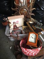 Overview of Americana decor lot including sun wall art, framed angel print, animal figurines, rocking reindeer sculpture, basket and clock parts
