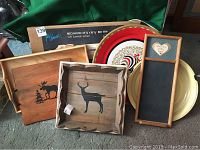 Photo shows the entire lot including the new in box wooden bed tray, wooden trays with animal silhouettes, chalkboard, and enamel and metal serving platters stacked and arranged together.