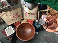 Overview of decorative containers including a large wooden bowl, metal pails, copper wind catcher, and framed pictures.