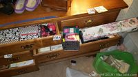 Photo showing opened drawers with decorative black and white stationery boxes, vintage Avon bottles in original packaging, and a floral-patterned storage box.