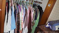 Photo showing multiple women's blouses, sweaters, and a jacket on hangers in a closet