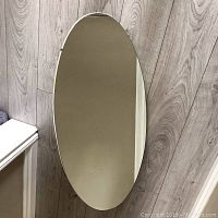 Front view of the oval mirror showing reflective surface and condition including some wear and scratches.