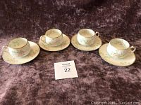 Four Limoges tea cups each on a matching saucer arranged in a row with lot number card visible.