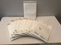 Twenty-five white bubble wrap lined padded mailer envelopes fanned out with one standing upright behind them.