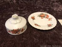 Butter dish components: domed lid with floral design and base plate with matching floral pattern on dark background.