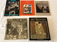 Top view of all five art books laid out on a white surface, showing covers of Schiele, a modern art book, I Galliari in Italian, a black and white historical art scene, and an Art Nouveau book.