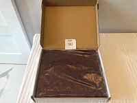 Photo of the burgundy photo album sealed inside a cardboard box wrapped in plastic.