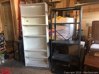Full view of white wood shelving unit and black metal shelving unit side by side in a garage setting.