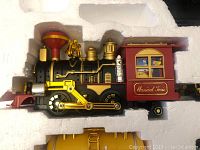 Close-up of black and gold locomotive with red passenger car attached, showing detailed design and colors.